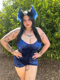 a woman in a blue velvet romper posing for a photo